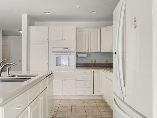 kitchen with white appliances, white cabinets, light tile patterned floors, and a sink