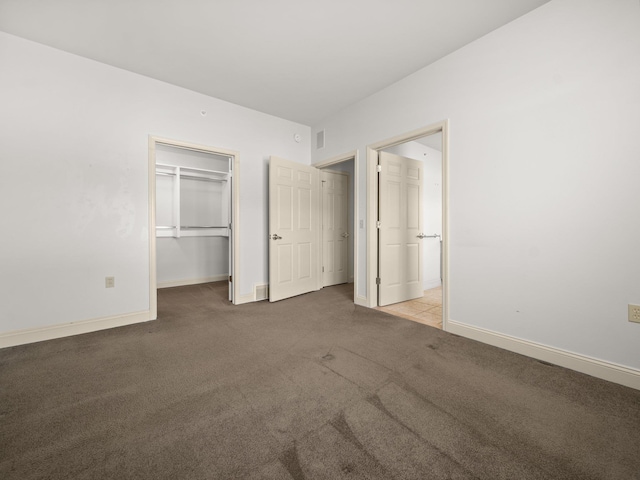 unfurnished bedroom with baseboards, carpet floors, a closet, and a walk in closet