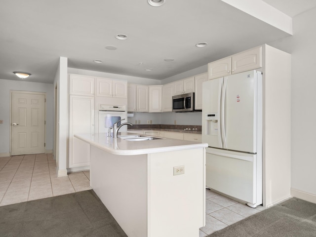 kitchen with a sink, white appliances, white cabinets, and light tile patterned floors