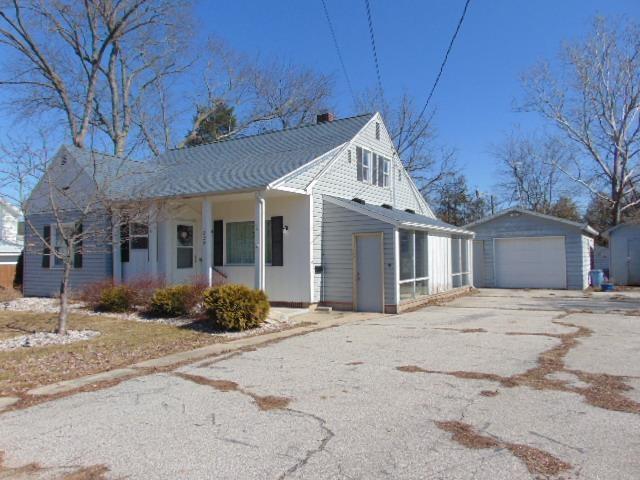 view of front facade with aphalt driveway, covered porch, an outbuilding, and a garage