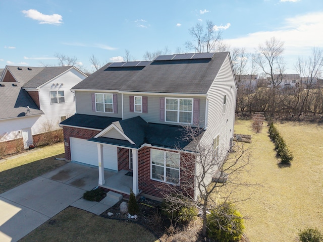 traditional-style house with brick siding, solar panels, driveway, and a front lawn