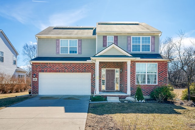 view of front of home featuring a front lawn, driveway, a garage, brick siding, and solar panels