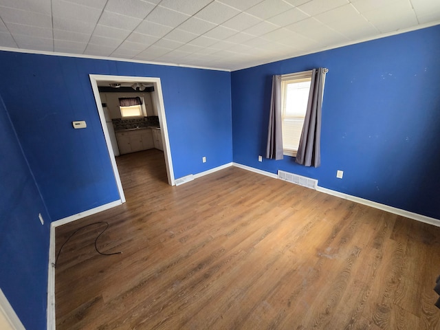 spare room with visible vents, baseboards, and wood finished floors