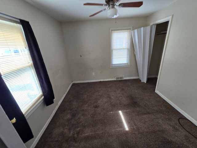 carpeted spare room with baseboards, visible vents, and ceiling fan