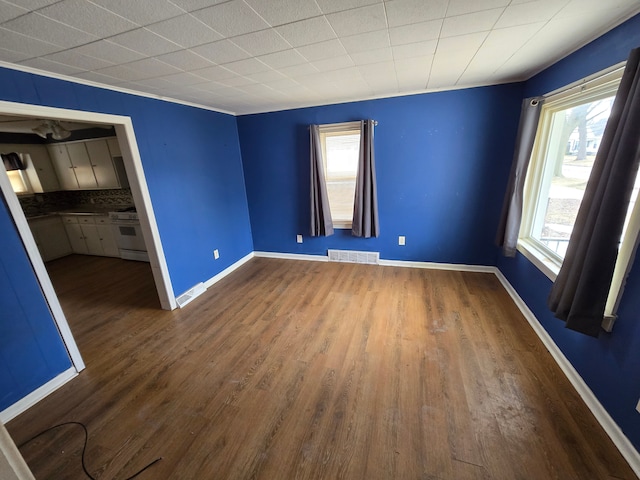 spare room with visible vents, baseboards, and wood finished floors