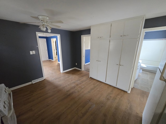 unfurnished bedroom featuring ceiling fan, a closet, baseboards, and wood finished floors