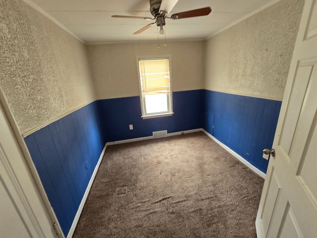 spare room featuring a wainscoted wall, ornamental molding, visible vents, and carpet floors