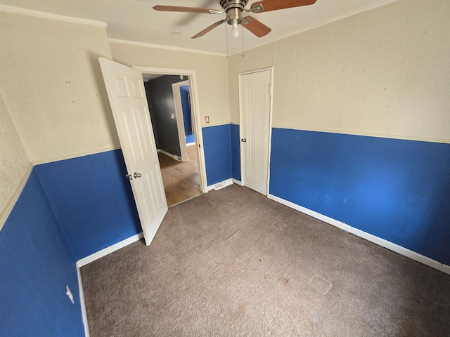 carpeted spare room with baseboards, ceiling fan, and ornamental molding