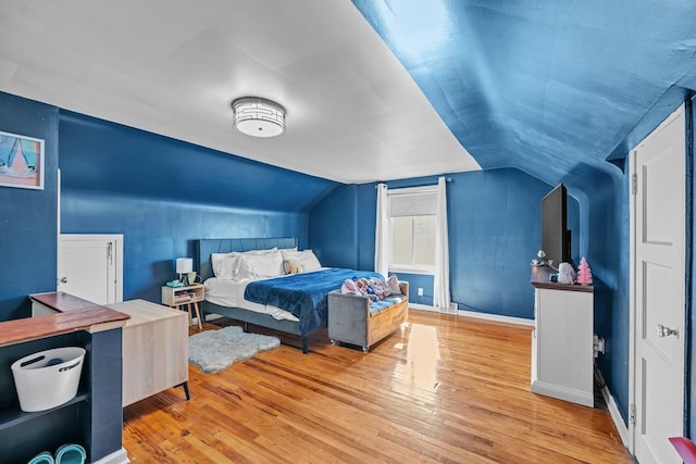 bedroom with baseboards, wood-type flooring, and lofted ceiling