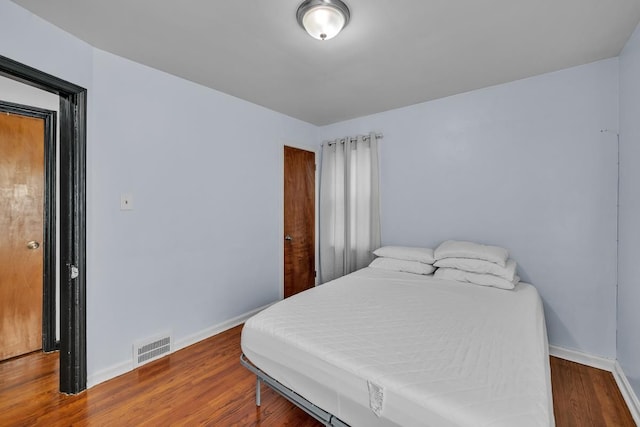 bedroom with visible vents, baseboards, and wood finished floors