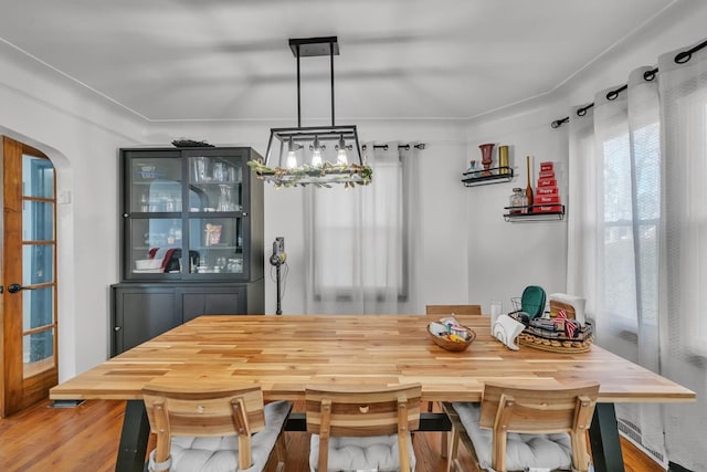 dining room featuring wood finished floors and arched walkways