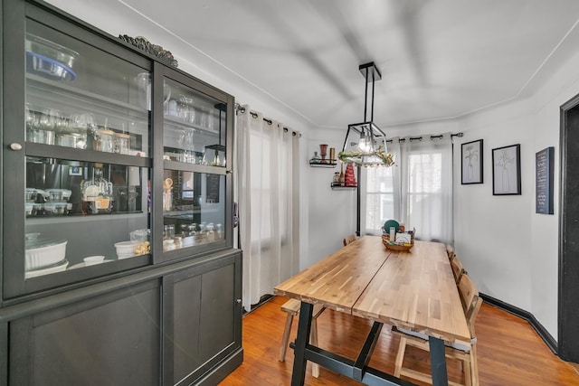 dining room featuring a chandelier, baseboards, and wood finished floors