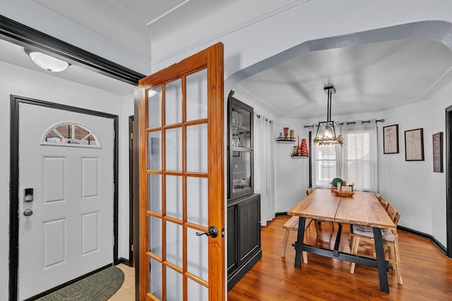 foyer featuring arched walkways, an inviting chandelier, and light wood-style flooring