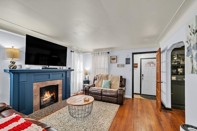 living room featuring a fireplace with flush hearth, wood finished floors, and baseboards