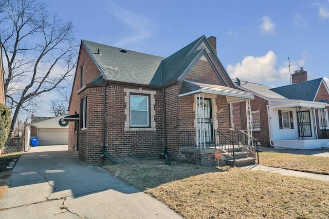 view of front facade featuring a garage, an outbuilding, roof with shingles, and brick siding