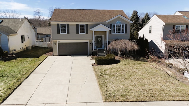 raised ranch with a front lawn, an attached garage, driveway, and a shingled roof