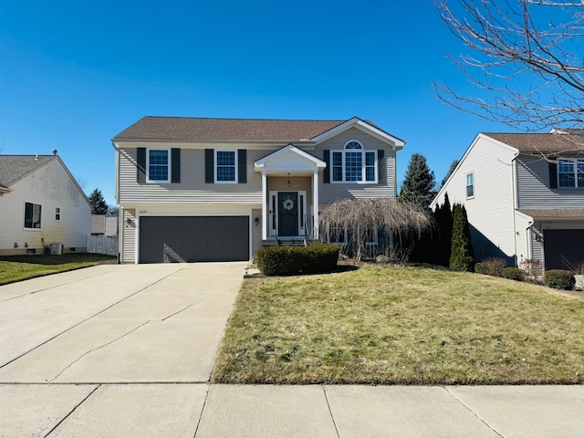 raised ranch featuring central AC unit, driveway, an attached garage, and a front yard