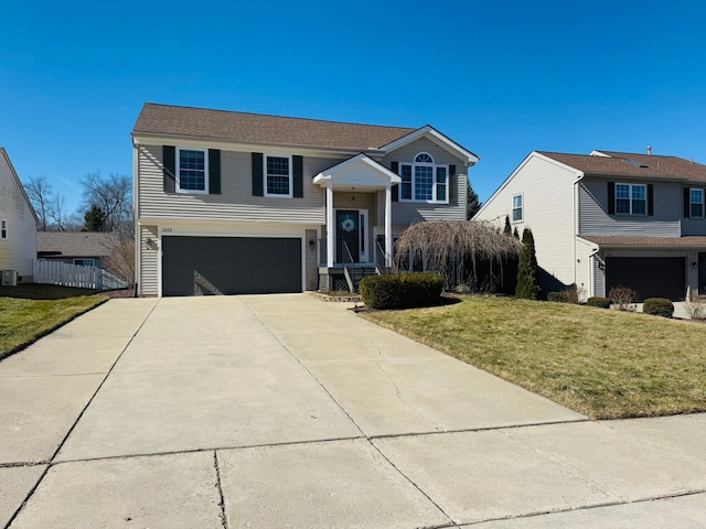 raised ranch featuring driveway, an attached garage, and a front yard