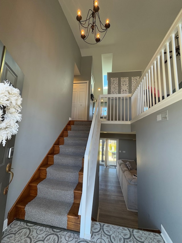 stairway featuring wood finished floors, baseboards, a chandelier, and high vaulted ceiling