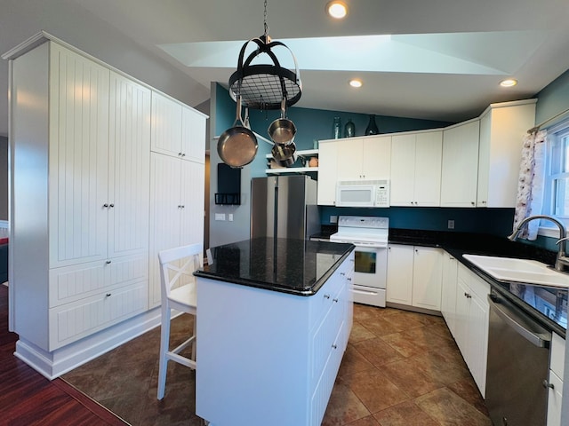 kitchen with lofted ceiling, a sink, white cabinets, appliances with stainless steel finishes, and a center island