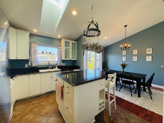 kitchen with glass insert cabinets, vaulted ceiling, recessed lighting, tile patterned floors, and a sink