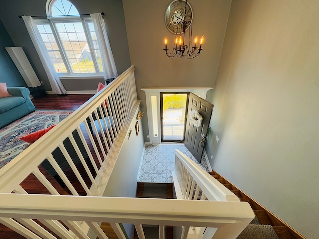 stairway featuring an inviting chandelier, a high ceiling, and baseboards