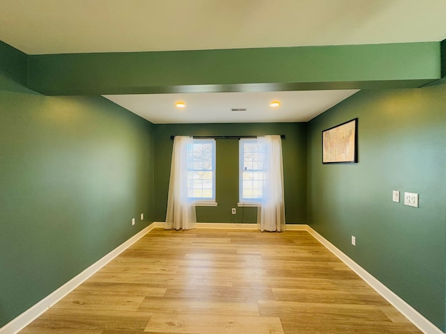 empty room with visible vents, light wood-style flooring, and baseboards