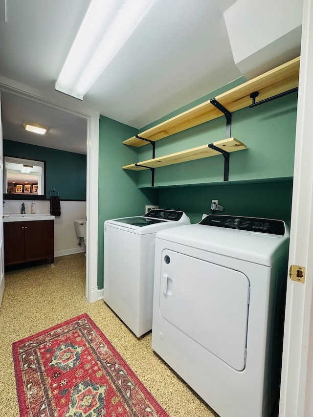 laundry area featuring laundry area, a sink, baseboards, and separate washer and dryer