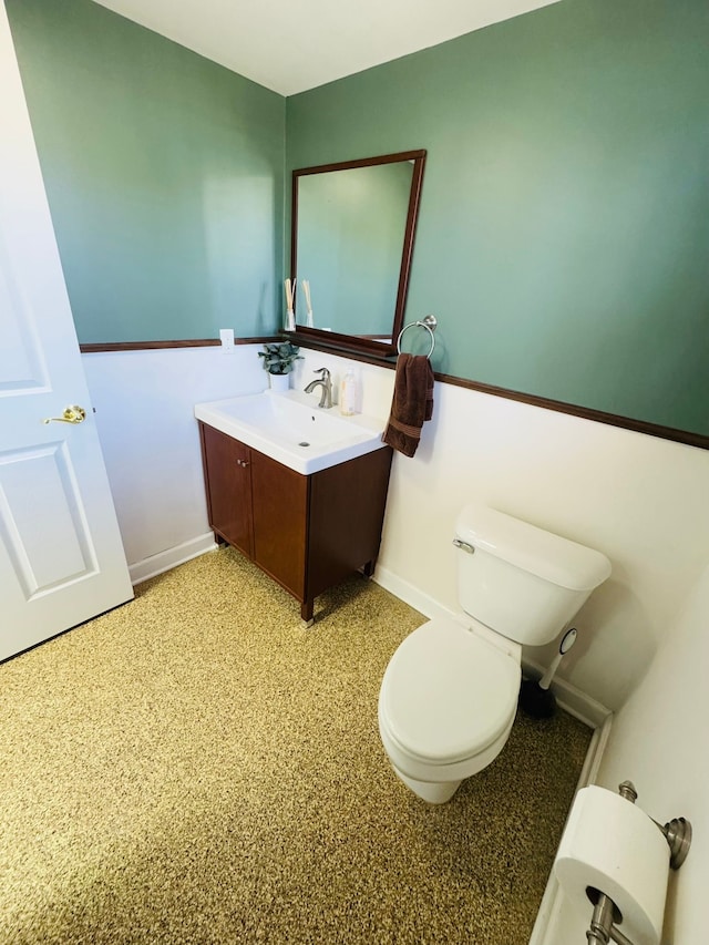 half bath with vanity, toilet, and baseboards