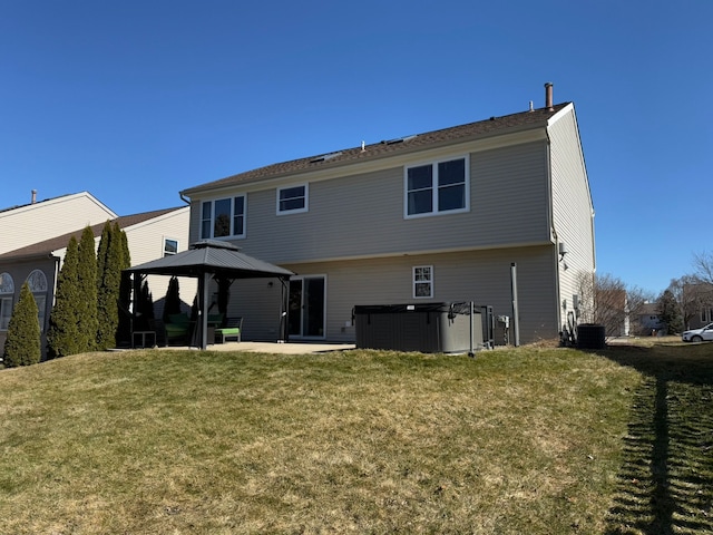 rear view of property with cooling unit, a hot tub, a gazebo, a patio area, and a lawn