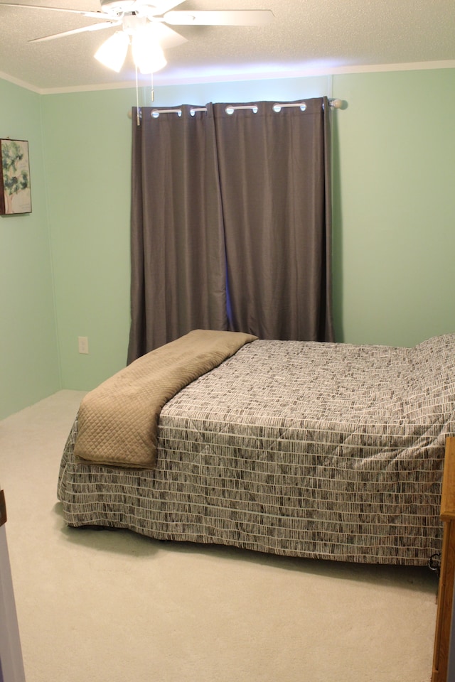 carpeted bedroom with a textured ceiling, ceiling fan, and ornamental molding