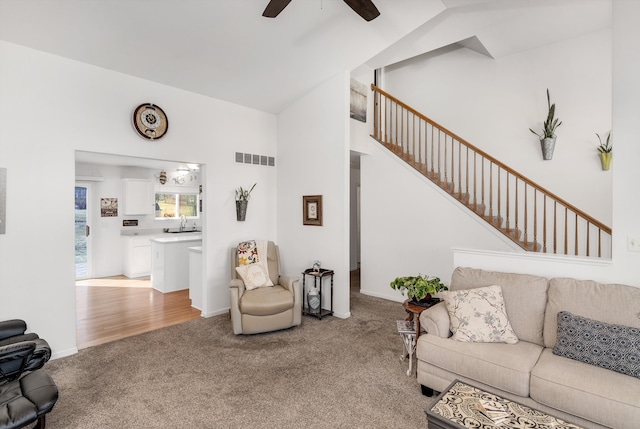 living area with ceiling fan, lofted ceiling, visible vents, and light carpet