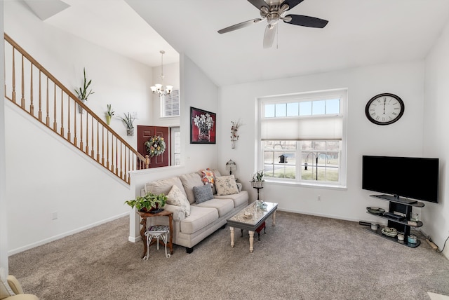 carpeted living room with stairway, ceiling fan with notable chandelier, and baseboards