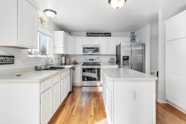 kitchen featuring a center island, light wood-type flooring, white cabinets, stainless steel appliances, and a sink