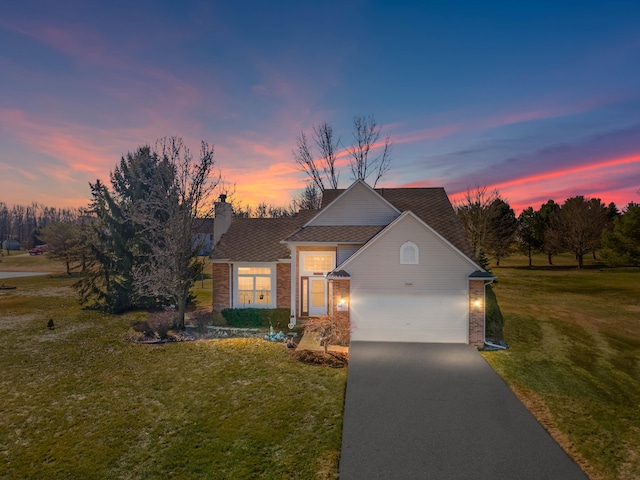 traditional home with a lawn, driveway, a garage, brick siding, and a chimney