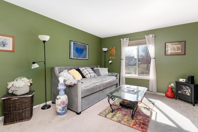 carpeted living area with a wood stove and baseboards