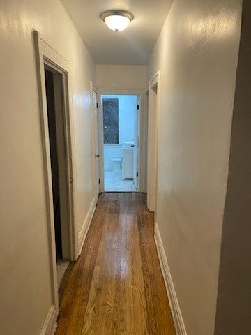 hall with dark wood-type flooring and baseboards