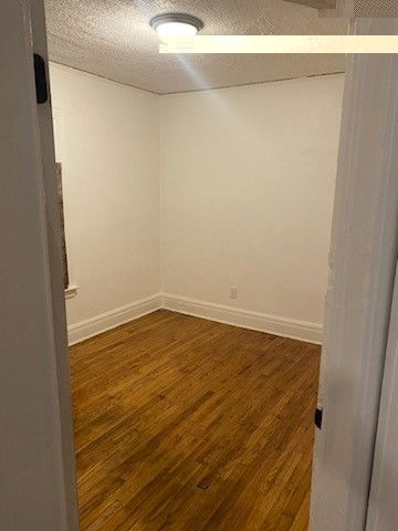 unfurnished room with dark wood-style floors, baseboards, and a textured ceiling