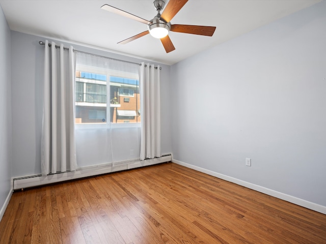 spare room with baseboard heating, ceiling fan, baseboards, and wood finished floors