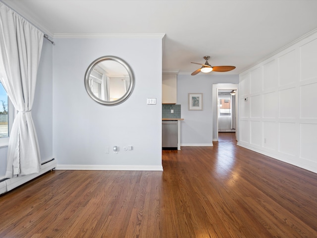 unfurnished living room featuring ceiling fan, a baseboard heating unit, ornamental molding, and dark wood finished floors