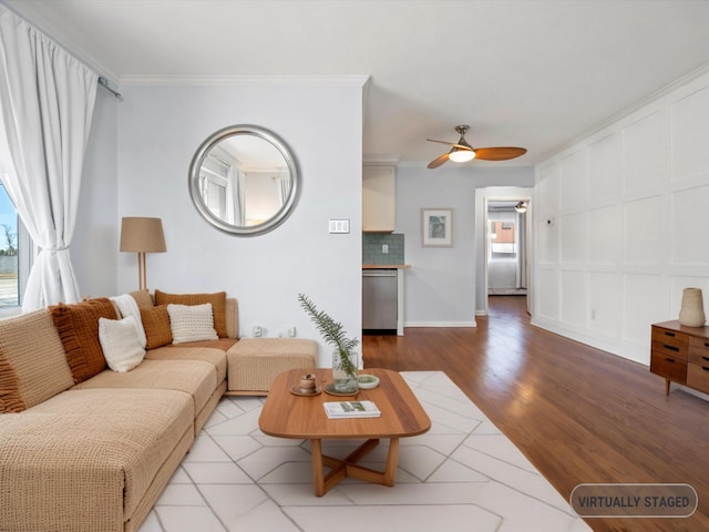 living room featuring a decorative wall, wood finished floors, ceiling fan, and ornamental molding