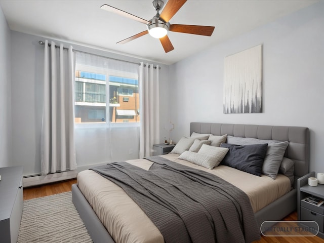 bedroom featuring ceiling fan, a baseboard radiator, and wood finished floors