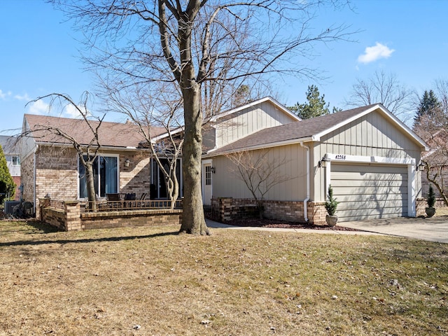 view of front of property featuring a garage, brick siding, concrete driveway, and a front yard