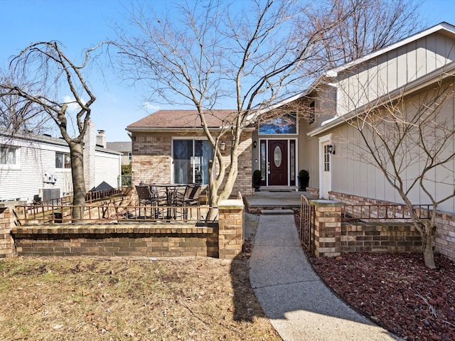 doorway to property with brick siding and central AC unit