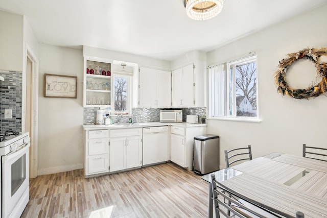 kitchen featuring decorative backsplash, white appliances, a healthy amount of sunlight, and light countertops