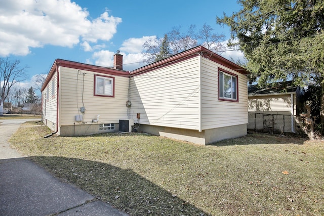 view of home's exterior featuring central AC unit, a lawn, and a chimney