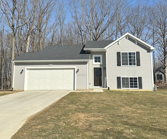 tri-level home with concrete driveway, a garage, roof with shingles, and a front lawn