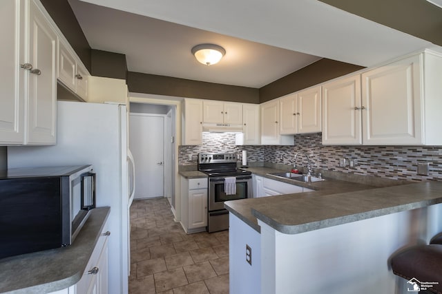 kitchen featuring dark countertops, under cabinet range hood, appliances with stainless steel finishes, a peninsula, and a sink