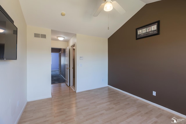 spare room with visible vents, ceiling fan, baseboards, lofted ceiling, and light wood-style floors