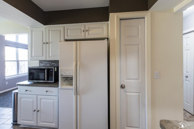 kitchen featuring white cabinetry, stainless steel microwave, tasteful backsplash, and white fridge with ice dispenser